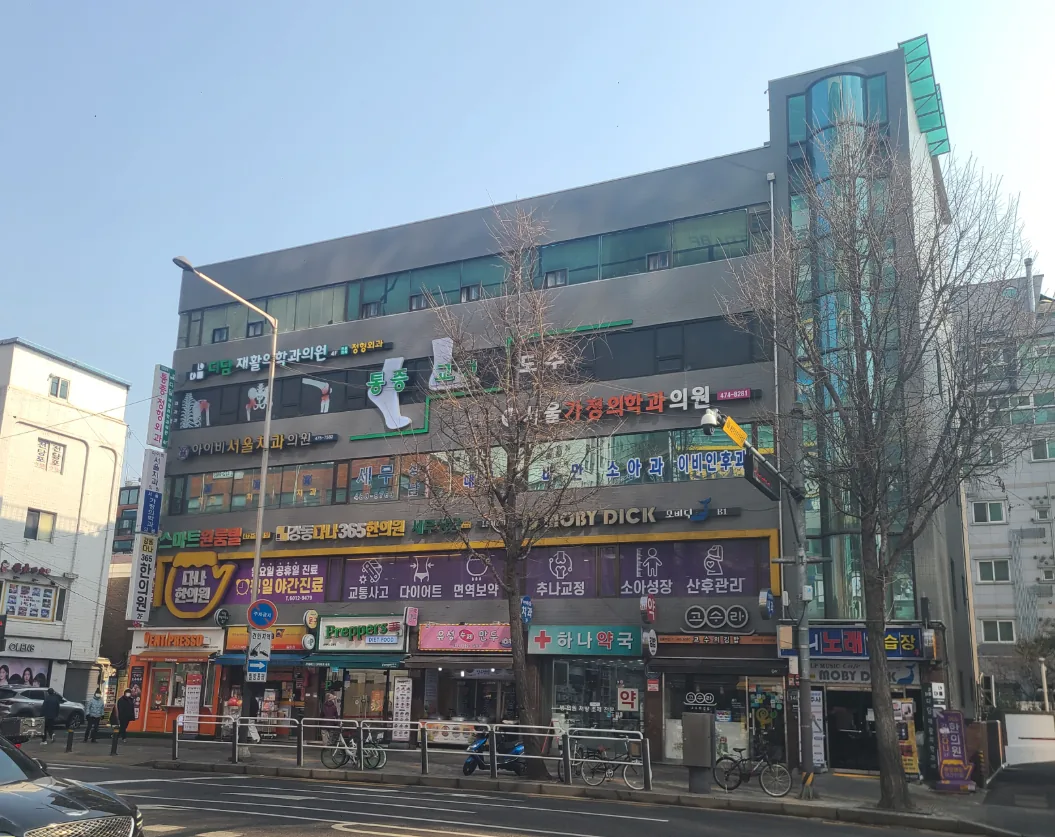 길동 411-1 대로변 전경 – 1층부터 상층까지 의원·약국 간판이 이어진 외관