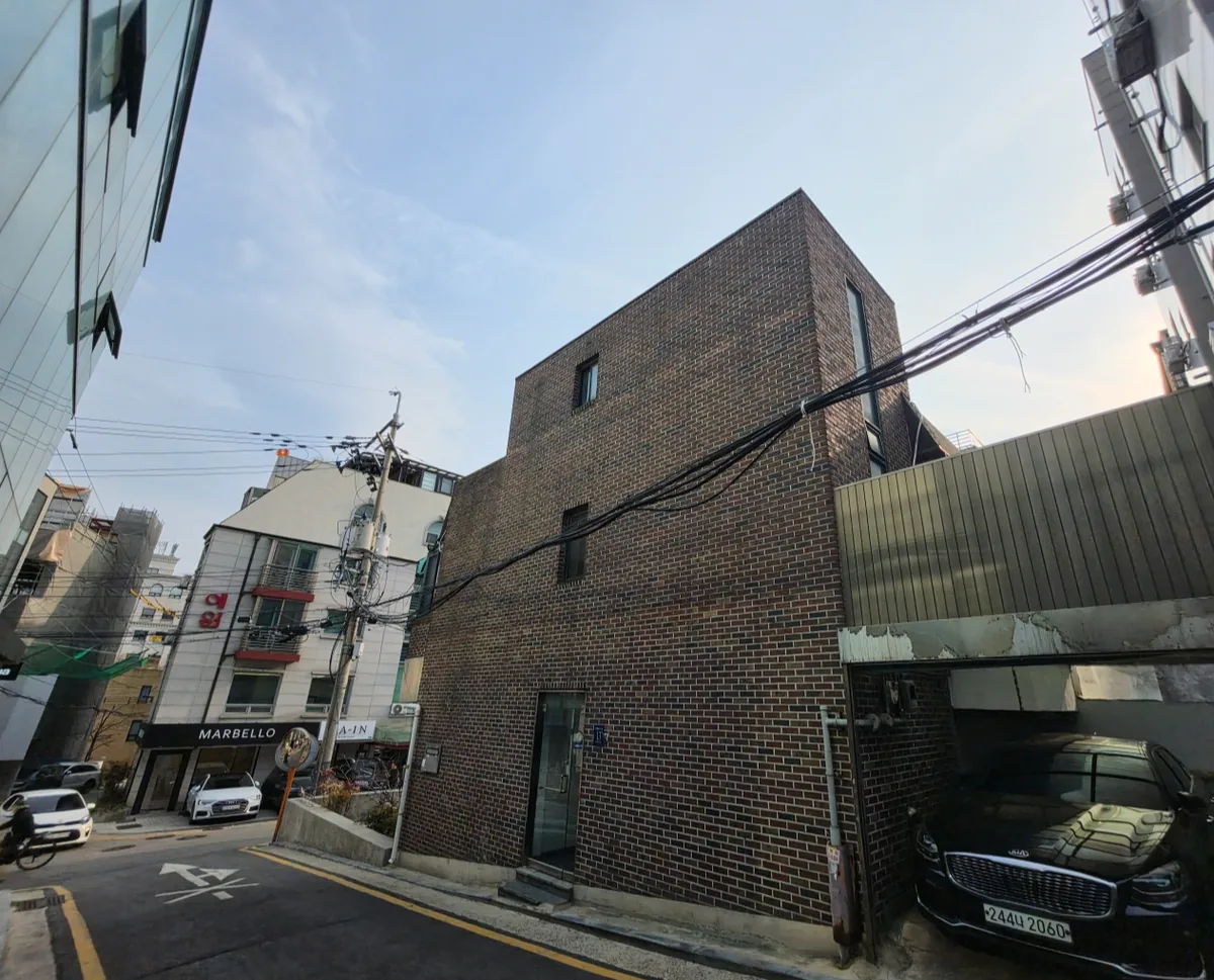 논현동 39-5 측면 – 맞은편 벽돌 신축 건물과 마주한 코너 도로